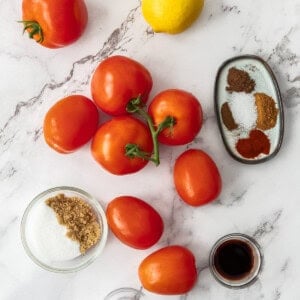 tomatoes, a lemon, and bowls of ingredients on a marbled board.