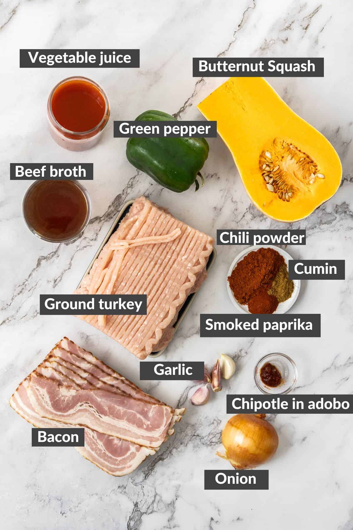 butternut squash, a pepper, bacon, ground turkey, and other ingredients on a marbled board.