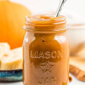 a jar of pumpkin butter with a spoon sticking out of it.