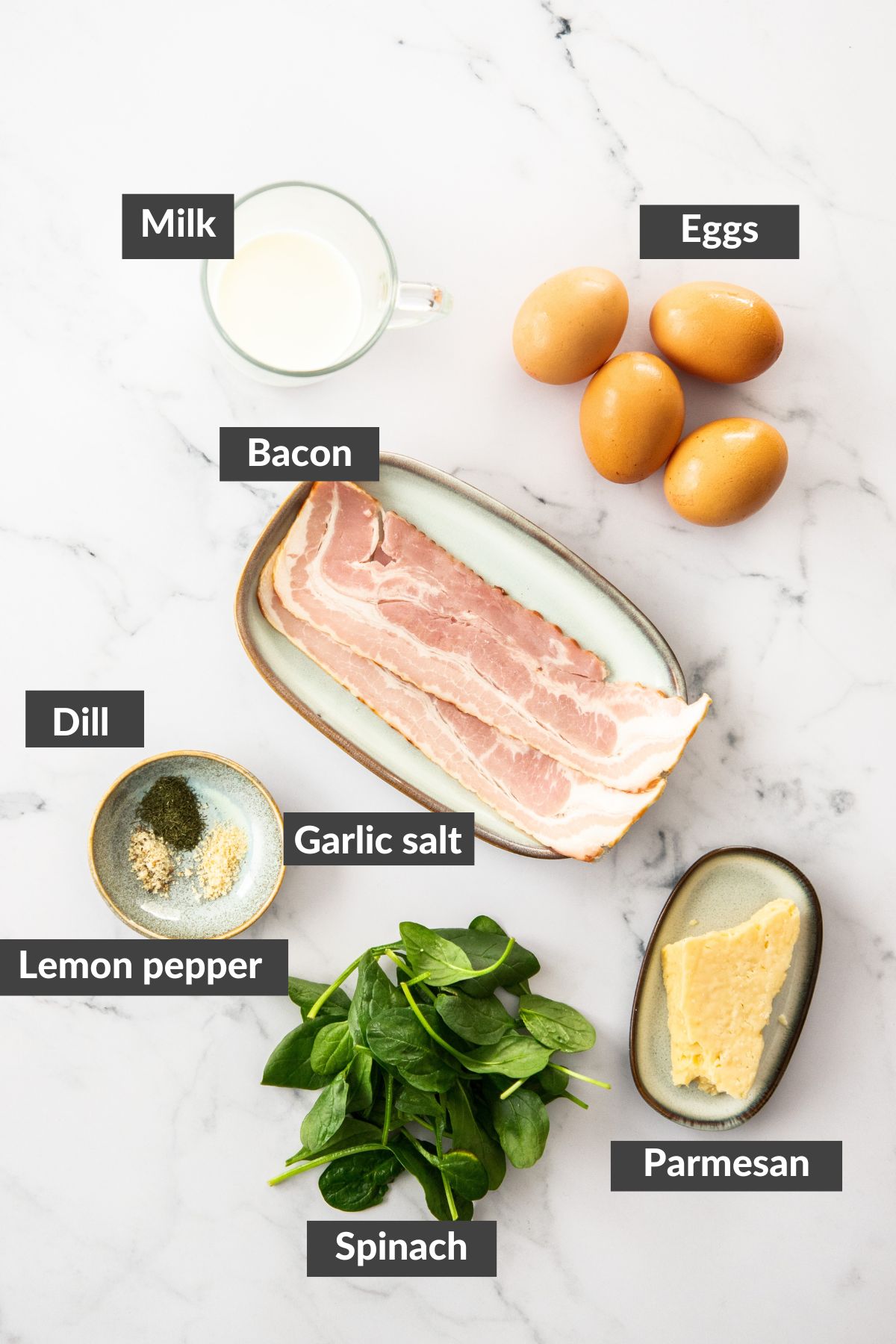 bacon, milk, cheese, spinach, eggs, and spices on a marbled board.