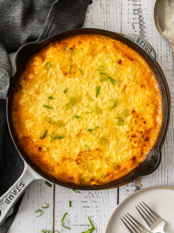 a black cast iron skillet of shepherd's pie with turkey topped with sliced green onions.