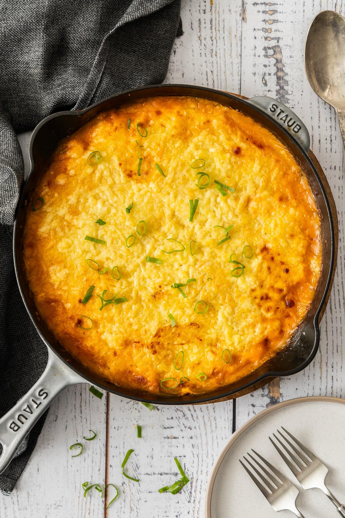 a black cast iron skillet of shepherd's pie with turkey topped with sliced green onions.
