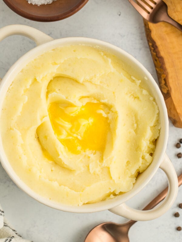 a white bowl with mashed potatoes topped with butter.