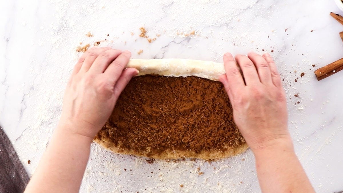 dough being rolled by two hands.