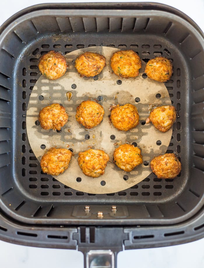 cooked crab cakes in an air fryer basket.
