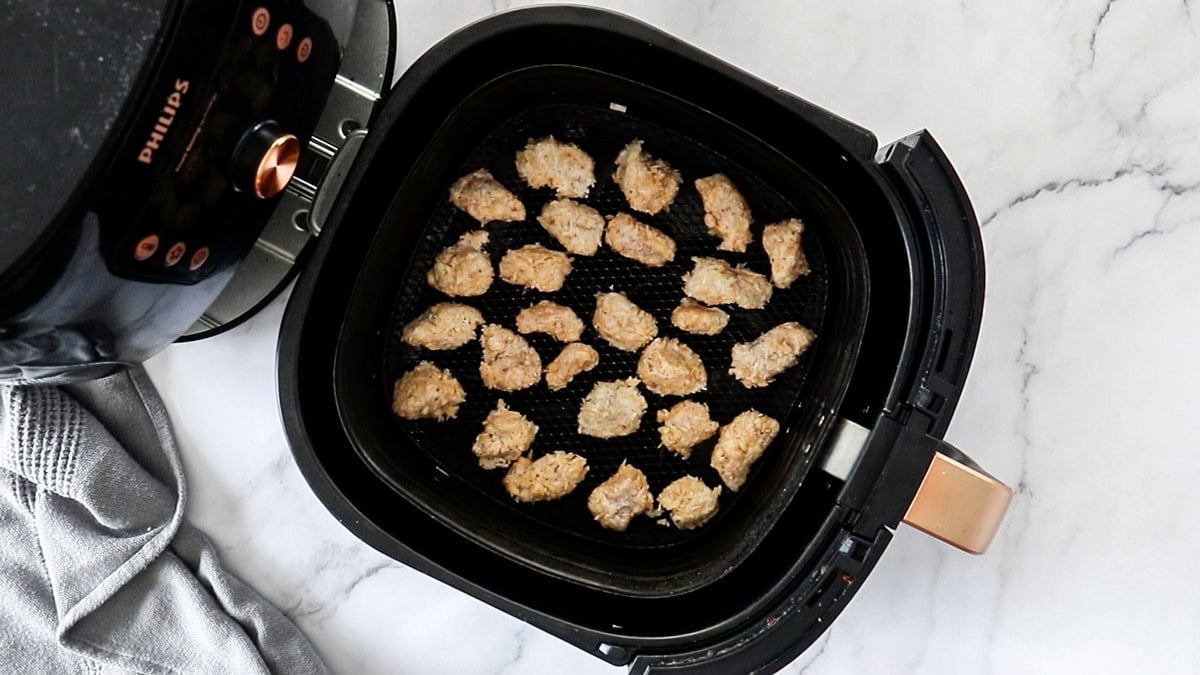 pieces of breaded chicken in an air fryer basket.