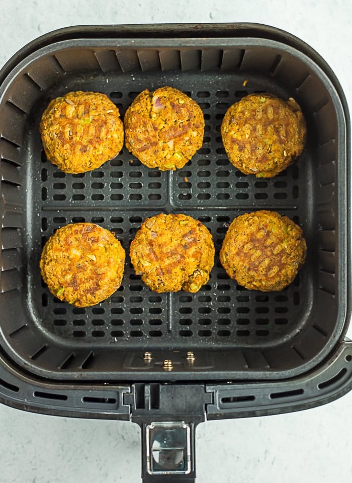 salmon patties being cooked in an air fryer.