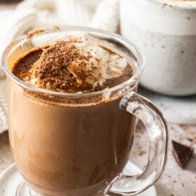 a glass mug of hot chocolate topped with whipped cream.