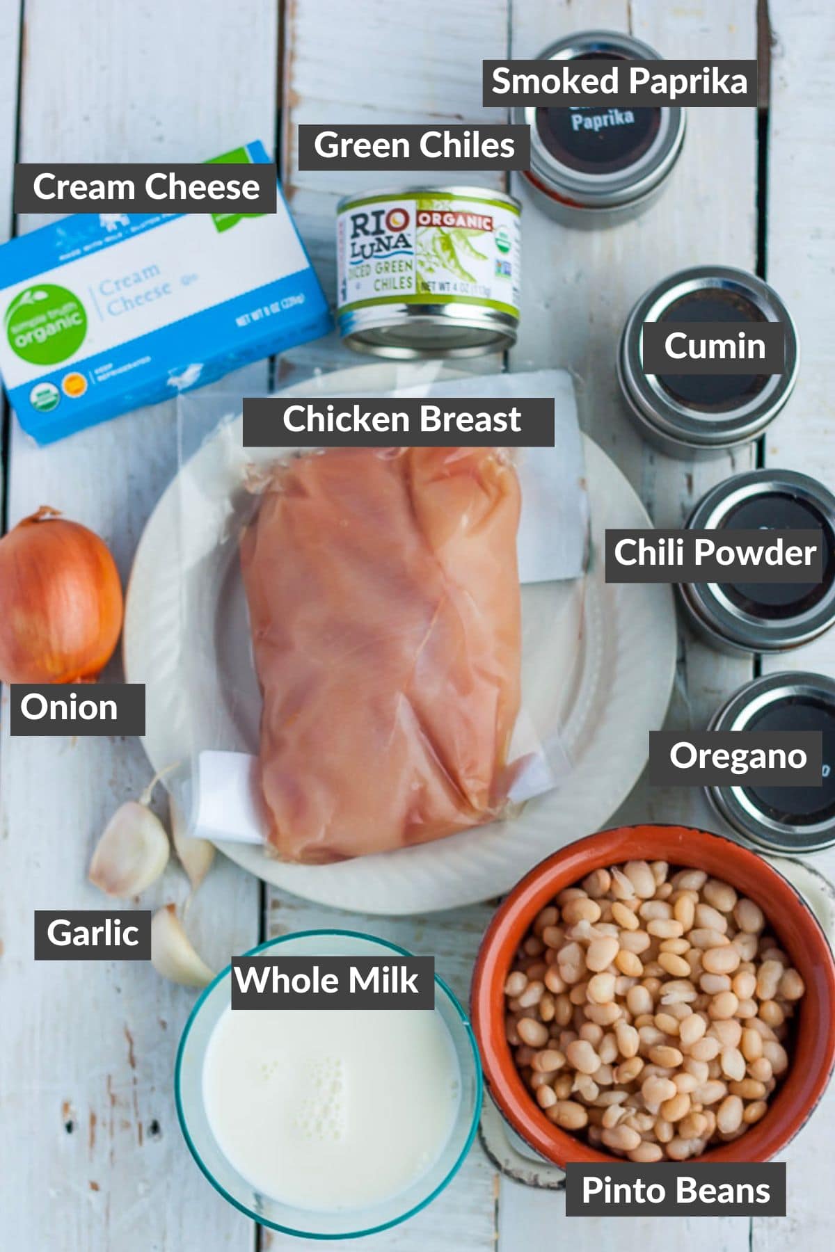 cream cheese, pinto beans, milk, onion, garlic, chicken breast, and other ingredients on a white board.