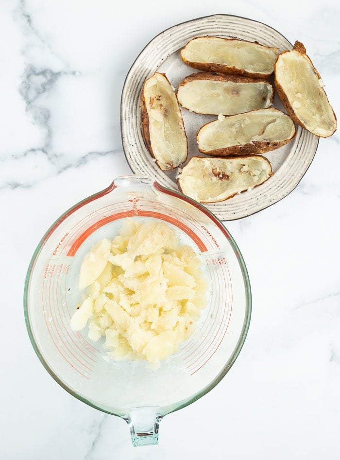 a bowl with potatoes in it and their skins on a plate.