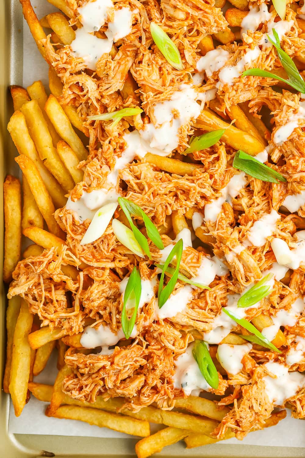 french fries topped with shredded buffalo chicken topped with ranch and sliced green onions.