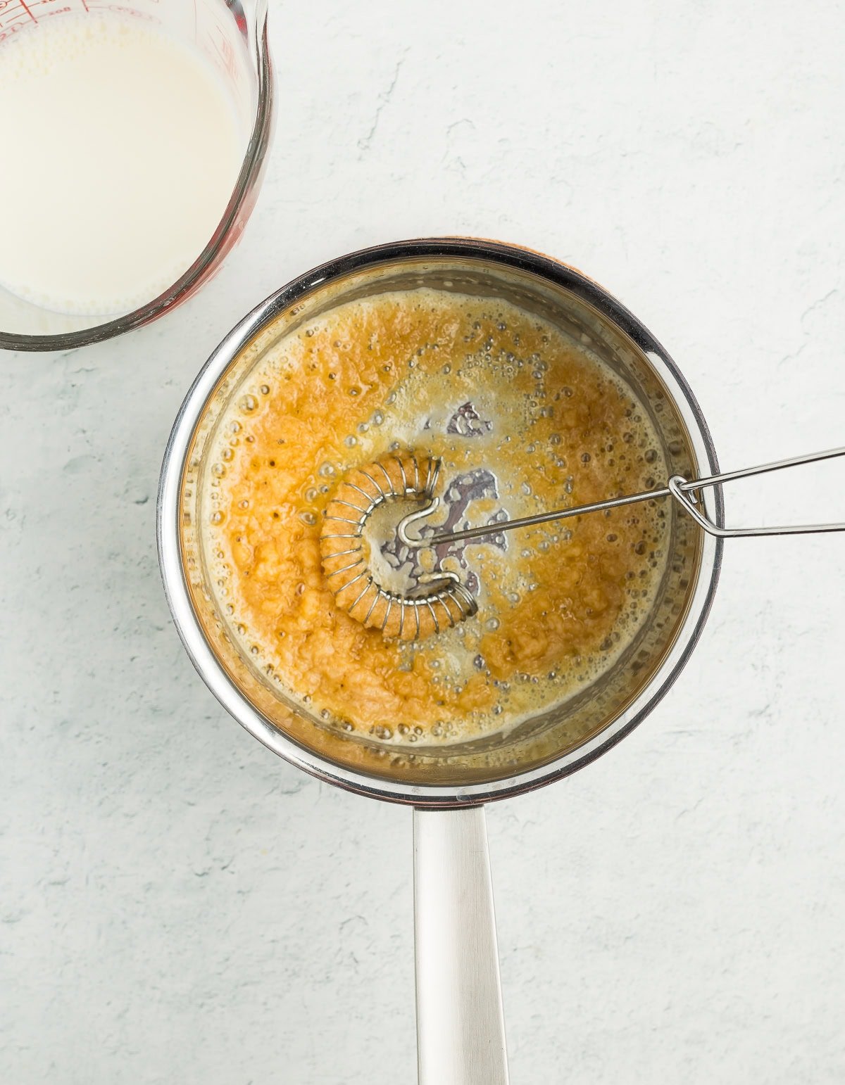 a whisk in a saucepan with a lump roux.