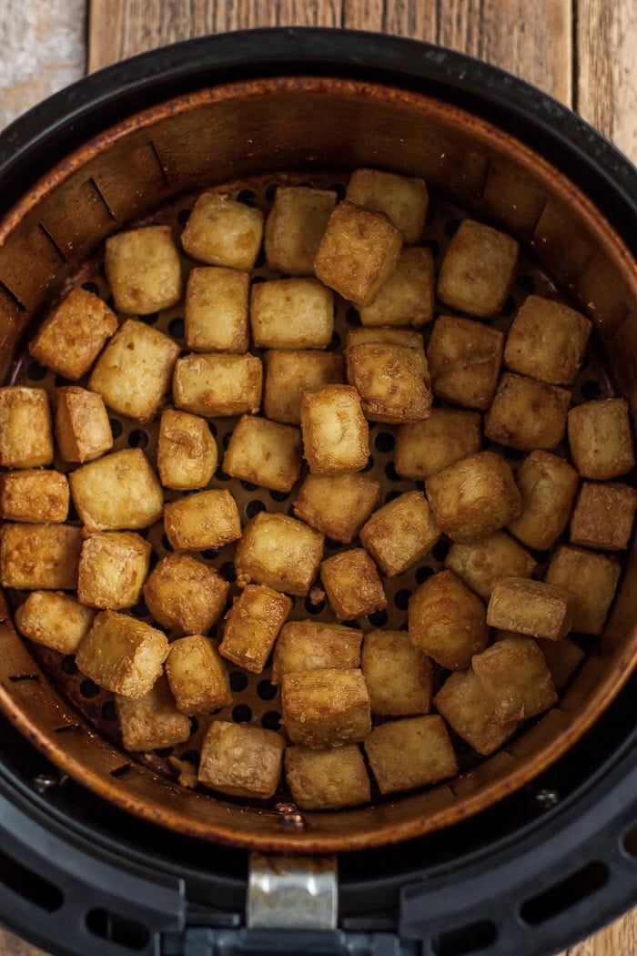 fried tofu cubes in an air fryer basket.