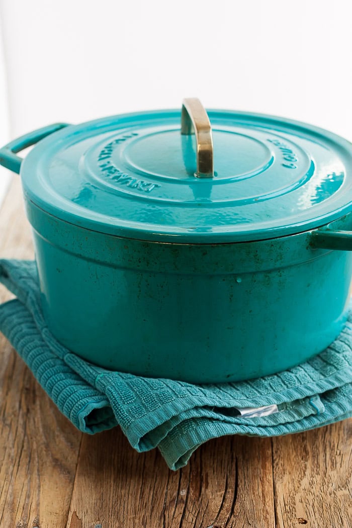 a teal casserole dish sitting on a plate with a towel.
