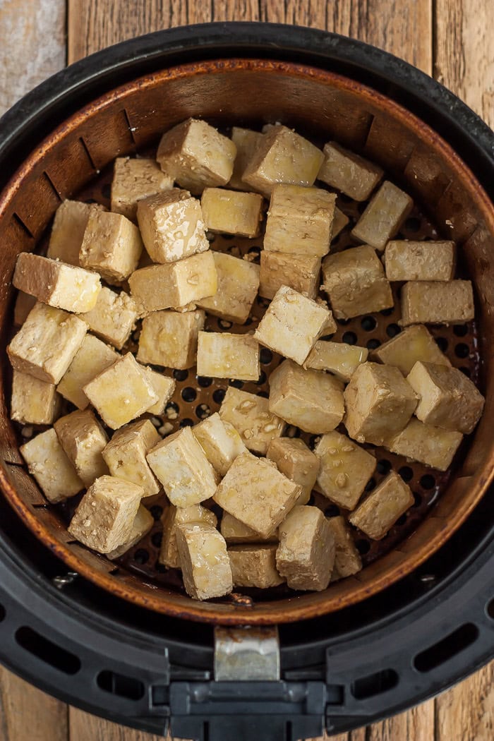 cubes of tofu in an air fryer basket.