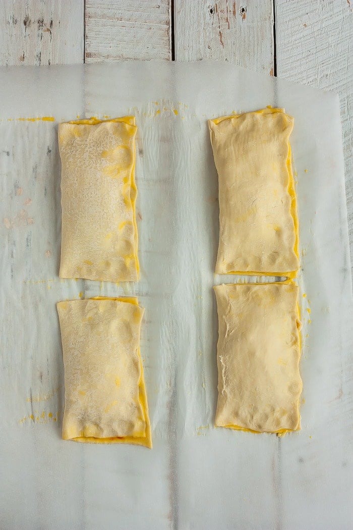 Folded pizza pockets on a piece of parchment.