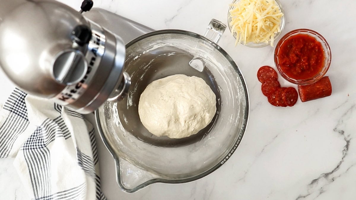 pizza dough being made in a stand mixer.