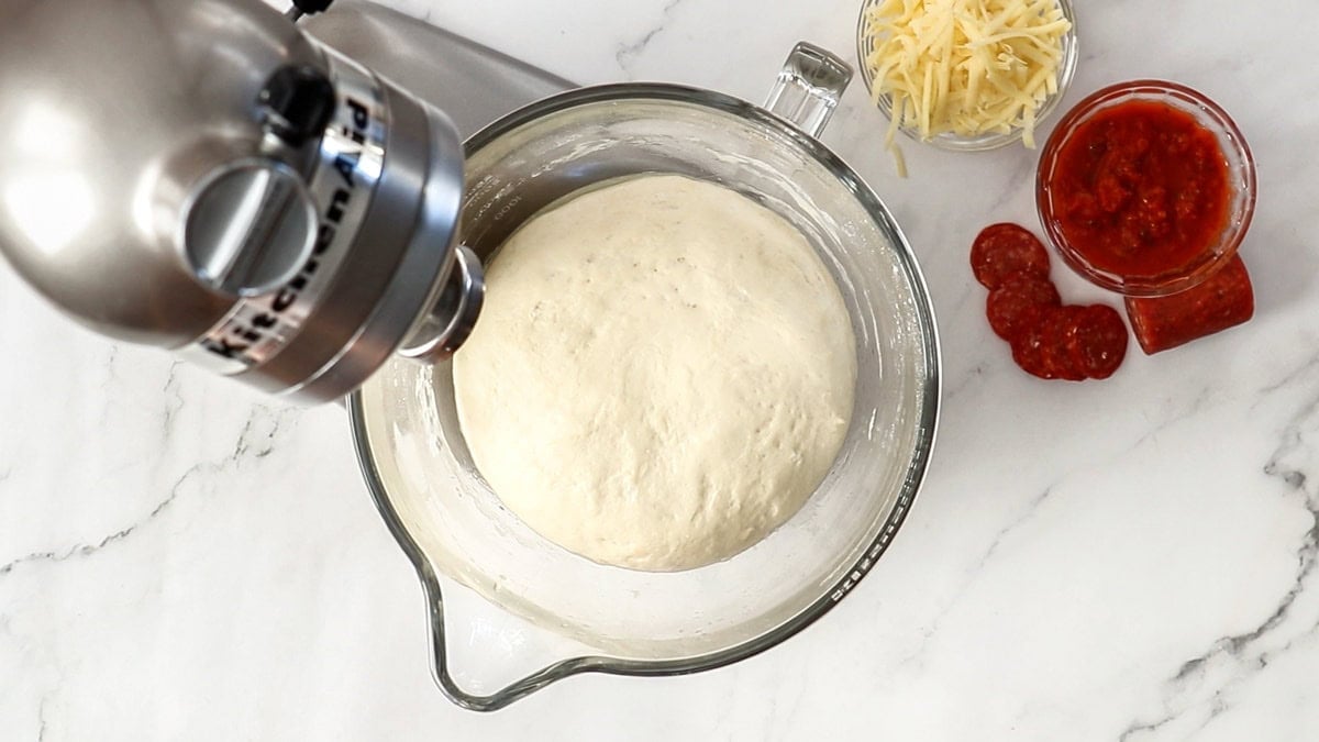 pizza dough being made in a stand mixer.