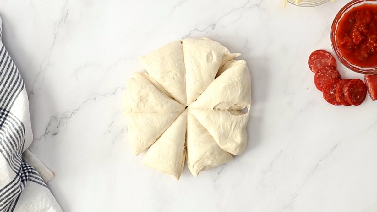 pizza dough cut into 8 pieces on a marbled board.