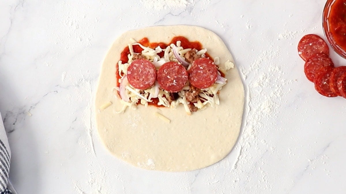 pizza toppings on half of an unbaked pizza crust.