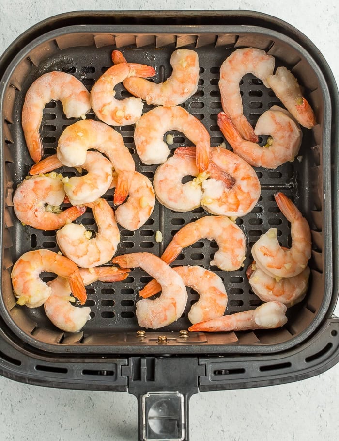 frozen shrimp in an air fryer basket.