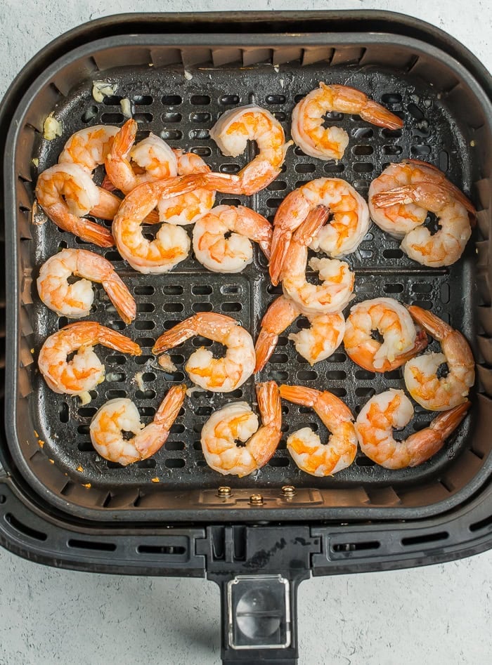 cooked shrimp in an air fryer basket.