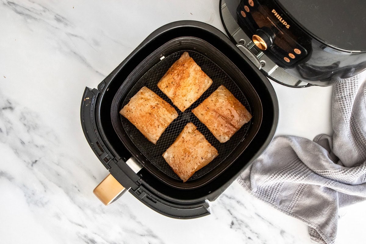 4 pieces of uncooked mahi mahi in an air fryer basket.