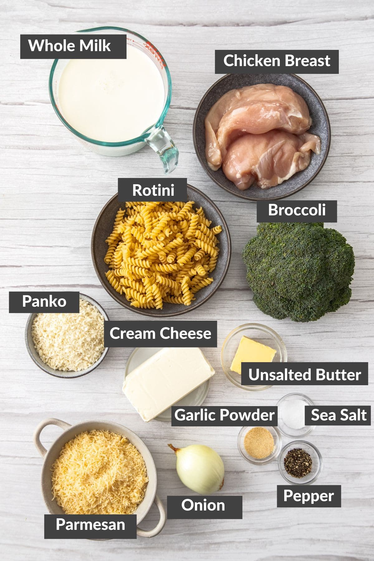 bowls of chicken noodles, cheese, milk, and a head of broccoli.