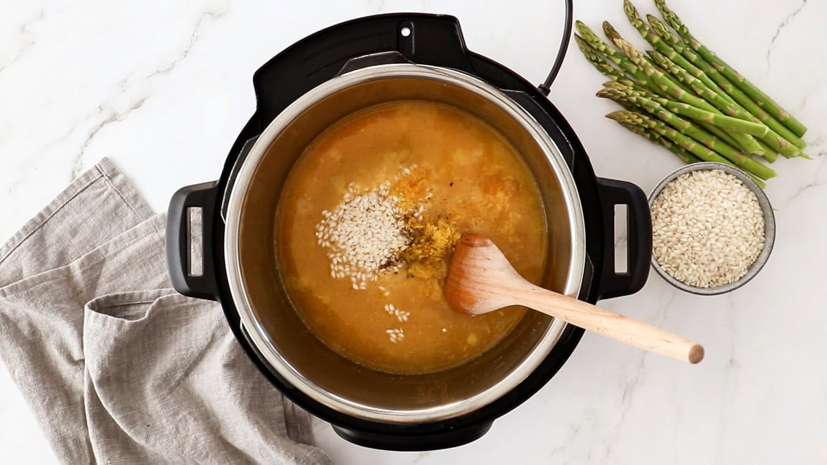 rice and broth and other ingredients in a pressure cooker.