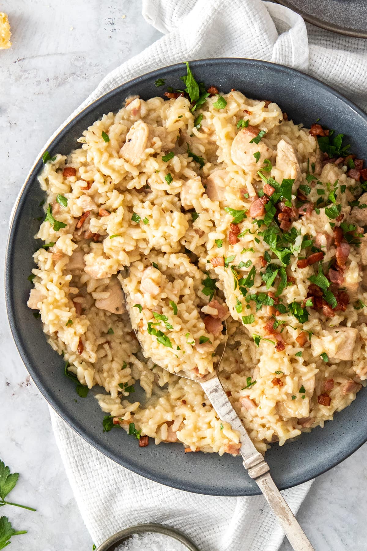 a green bowl with chicken and bacon risotto and a spoon.
