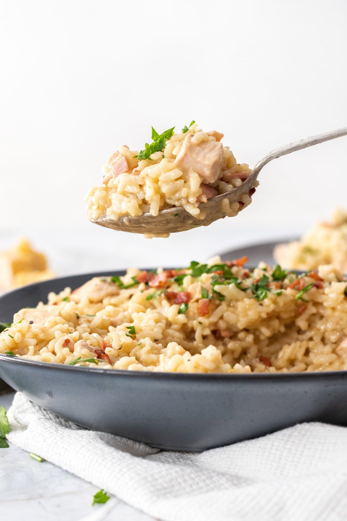 a spoonful of rice, chicken, and parsley hovering over a green bowl.
