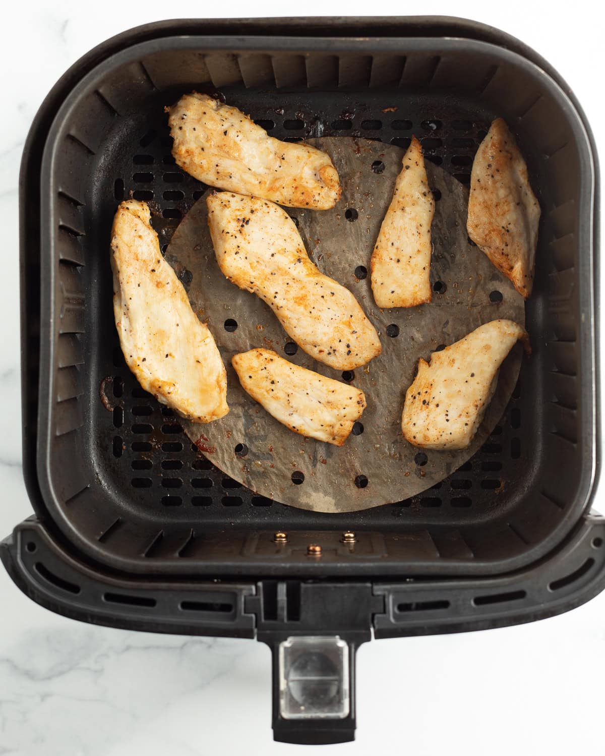 cooked grilled chicken in an air fryer basket.