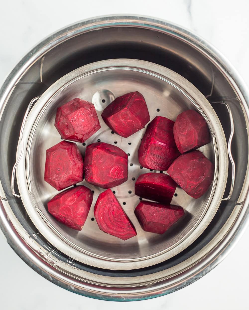uncooked beets in a steamer basket.
