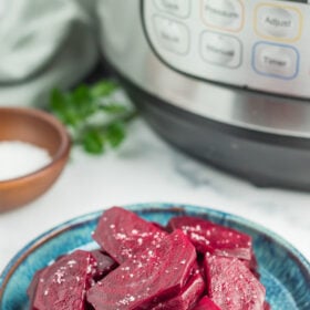 a teal plate with sliced beets topped with flaky sea salt and chopped parsley.