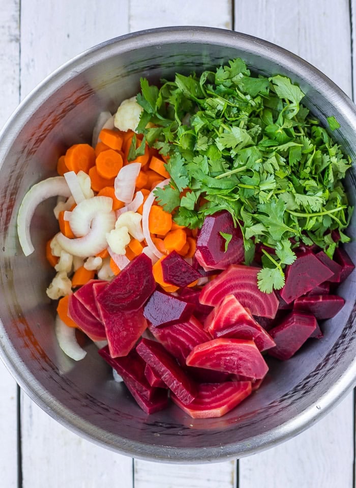 cilantro and other sliced veggies in a large stainless bowl.