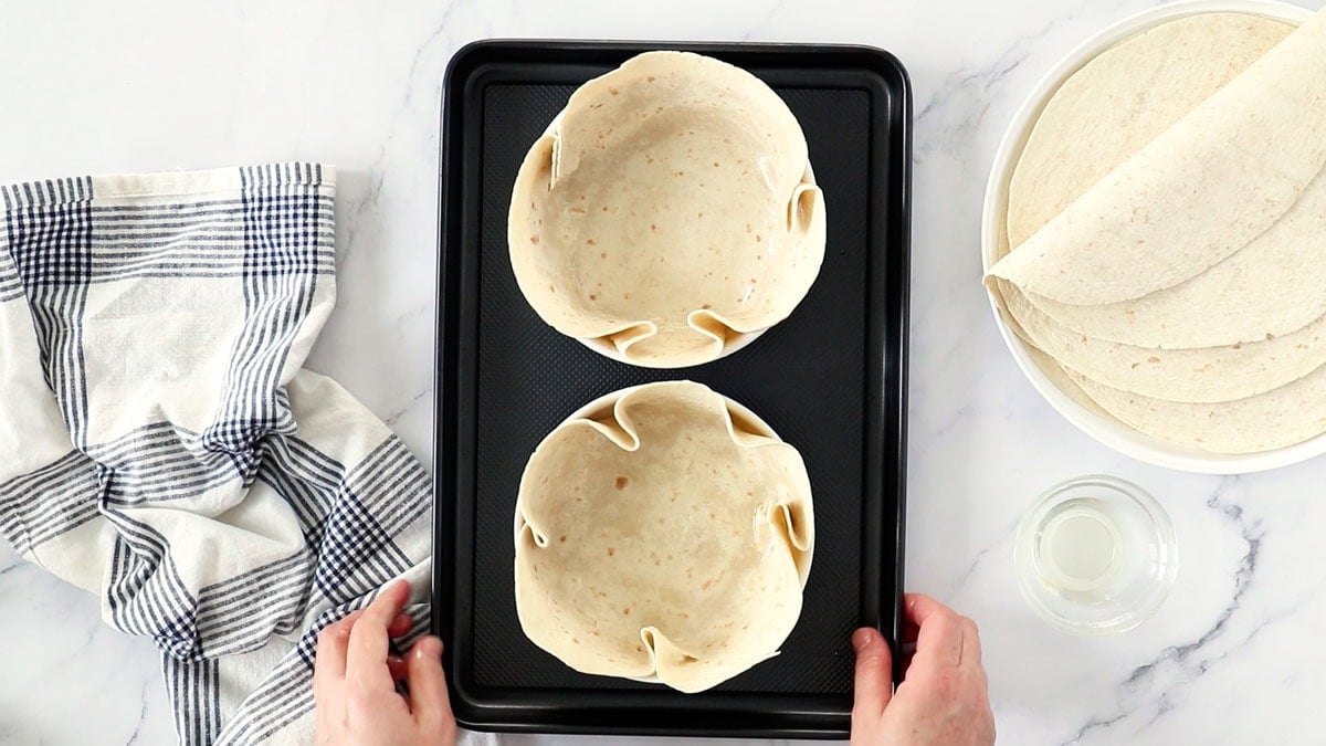 two tortillas in white bowls on a black tray.