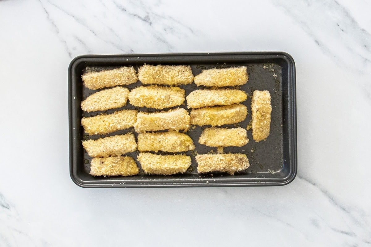 slices of breaded mahi mahi on a baking sheet.