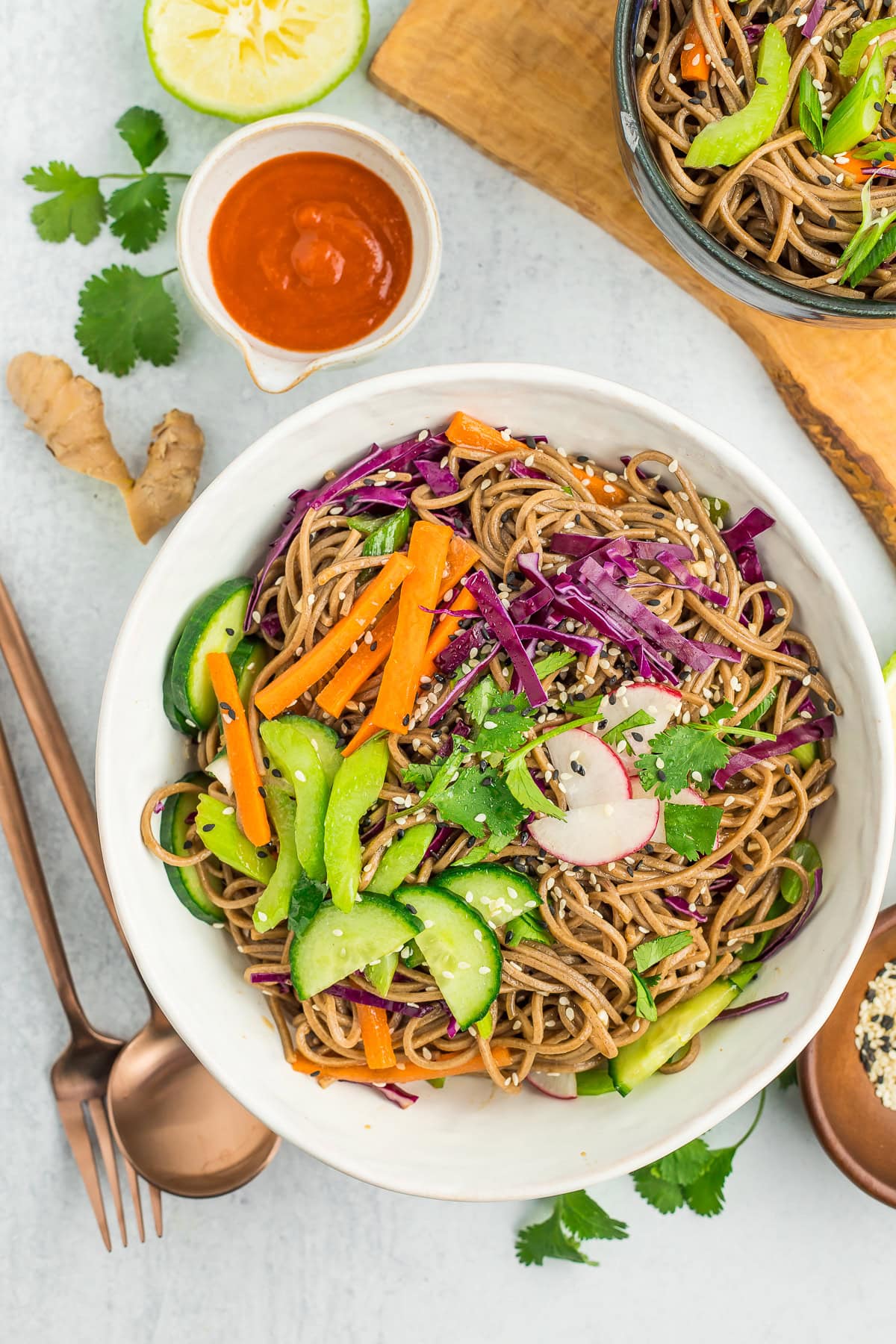 a white bowl with a cold noodle salad topped with veggies.
