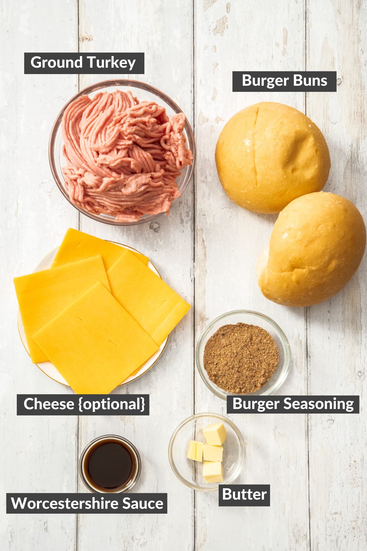 ground meat, buns, cheese, and other ingredients on a wooden board.