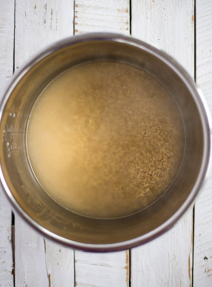 uncooked rice and water in a pressure cooker insert.