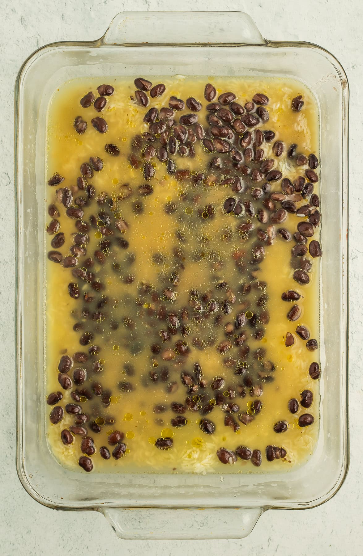a baking dish with black beans and chicken stock.