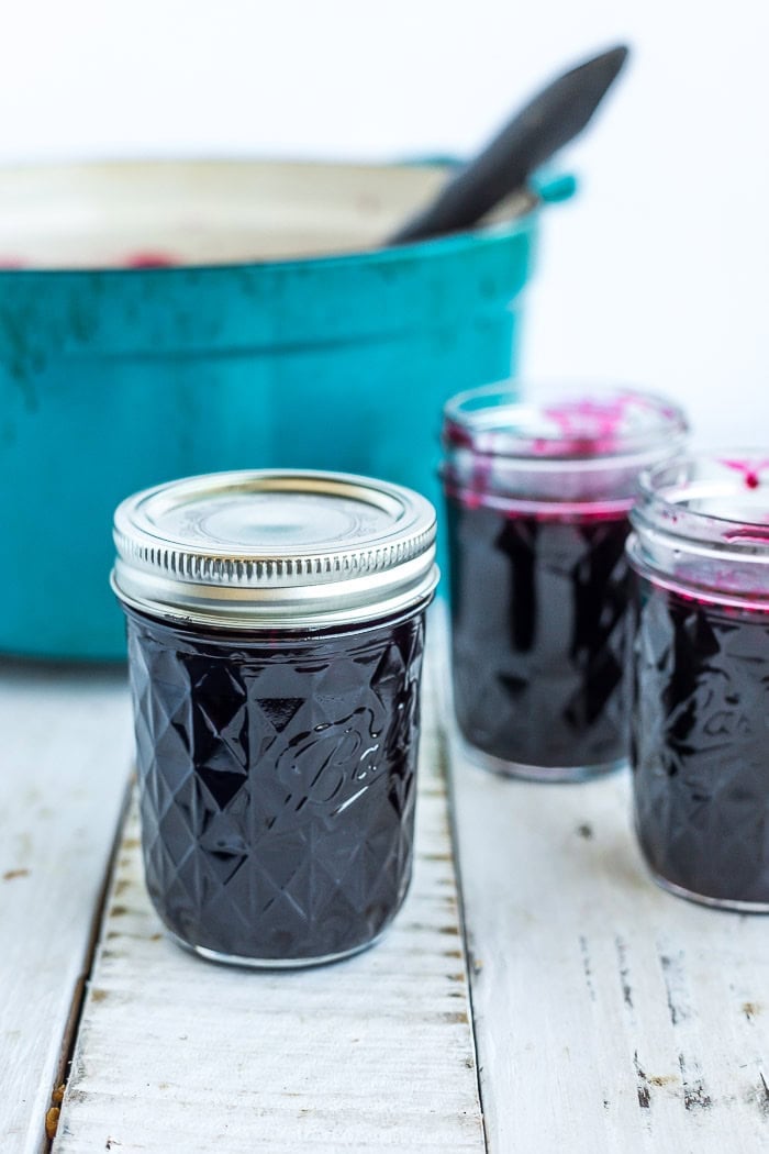 a mason jar with a lid and ring on it in front of a teal Dutch oven.