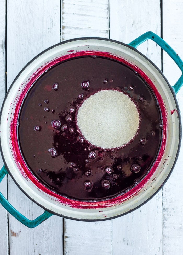berry sauce and sugar in a teal Dutch oven.