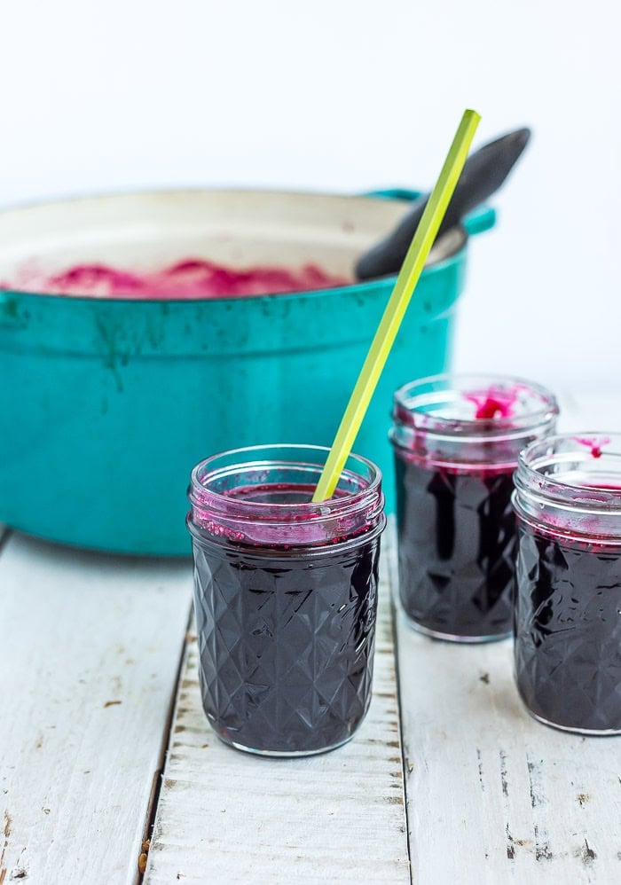 berry sauce in a canning jar with a green chopstick sticking out of it.