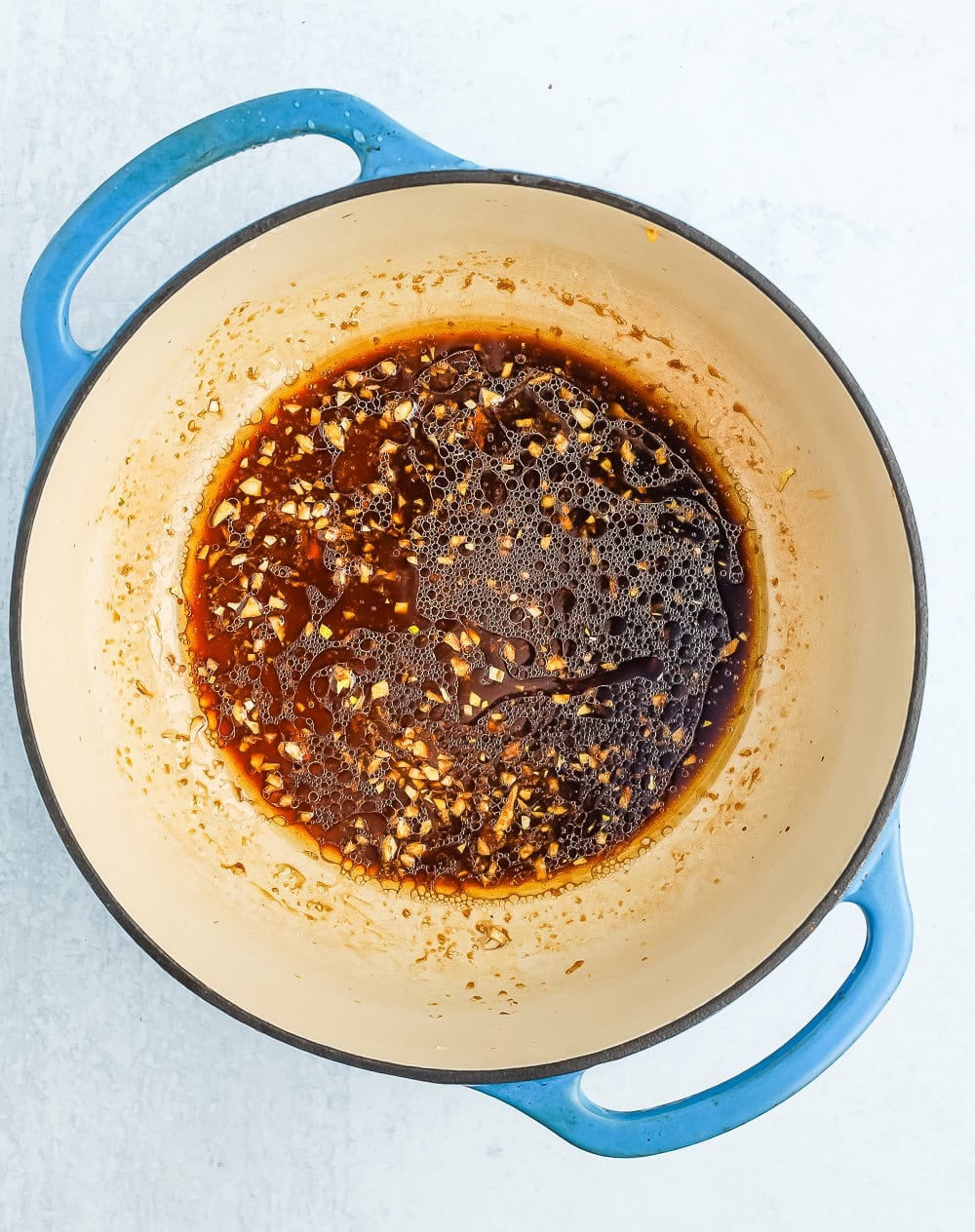 a sauce in a blue Dutch oven.