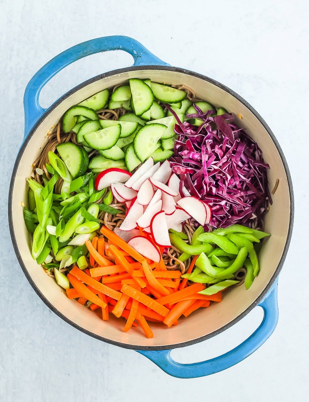 lots of chopped veggies in a blue Dutch oven.