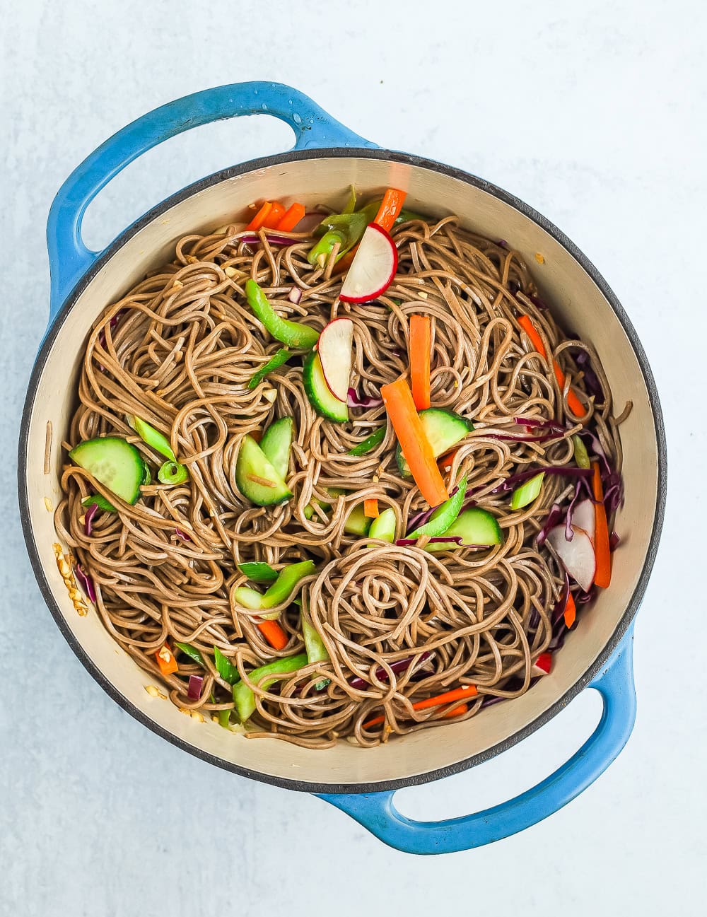 a blue Dutch oven filled with a cold veggie noodle salad.