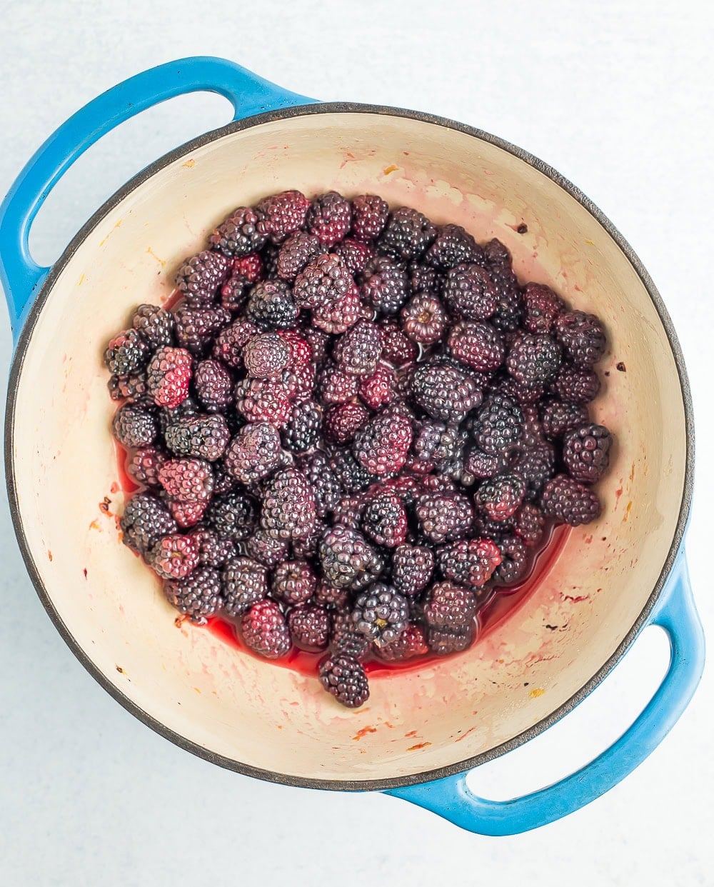 a blue dutch oven with blackberries.