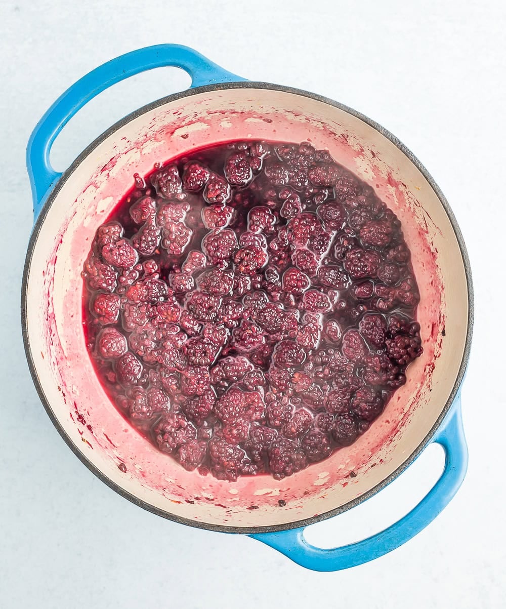 a blue dutch oven with berry sauce being cooked.