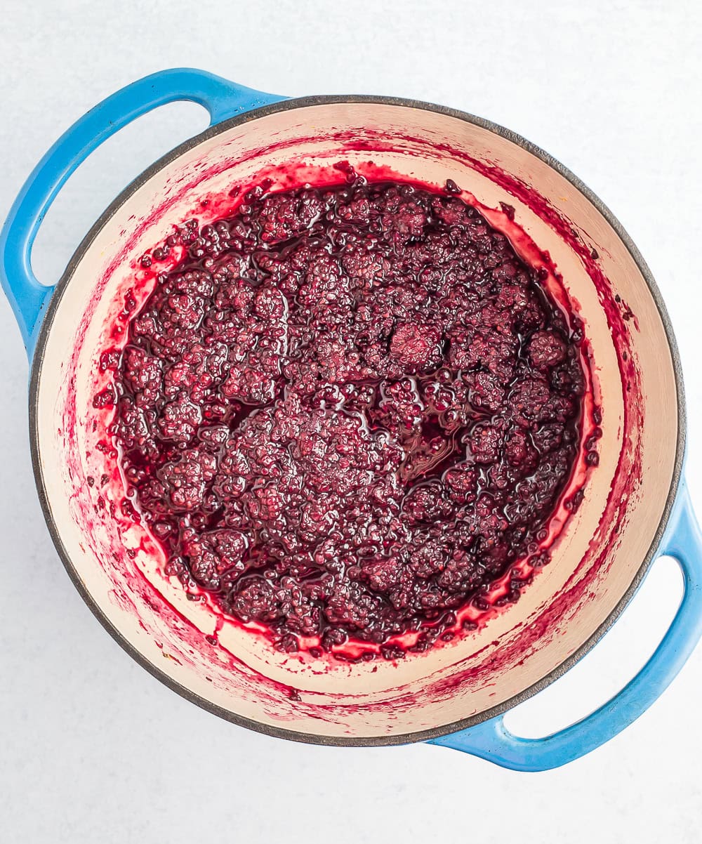 a blue dutch oven with berry sauce.